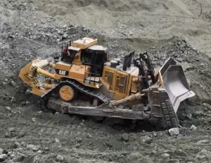Cat D11 dozer ripping hard ground in a mine pit, where abrasive conditions shorten undercarriage life